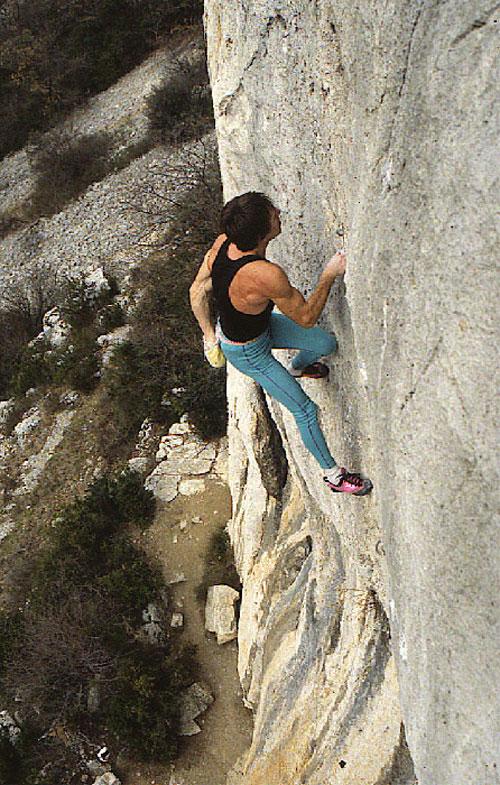man rock-climbing half way up a high rock