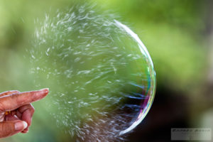 Picture of finger bursting a large bubble seen in slow motion