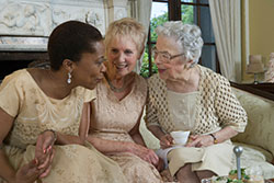 three senior women sat close on sofa chatting